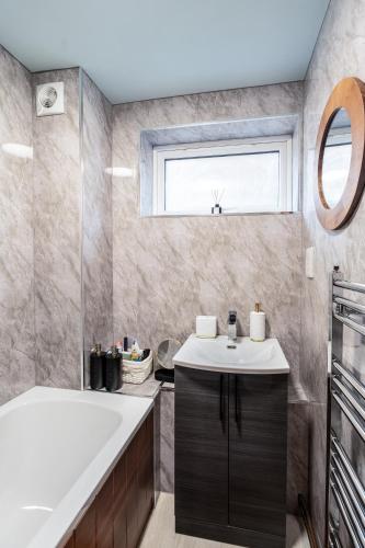 a bathroom with a tub and a sink and a window at The Blue Barbican Flat- spacious, stylish, in a perfect location and accessible in Plymouth