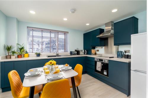 una cocina con armarios azules y una mesa con sillas amarillas en The Blue Barbican Flat- spacious, stylish, in a perfect location and accessible, en Plymouth