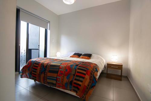 a bedroom with a bed with a colorful blanket on it at Departamento del Bosque equipado para 4 patio parrilla cochera cubierta in Maipú