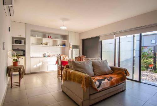 a living room with a couch and a kitchen at Depto del Bosque, 4 personas, patio, cochera cubierta ,parrilla in Maipú