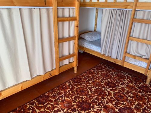 PanjakentにあるSalom Hostelの二段ベッド2台とラグが備わる客室です。