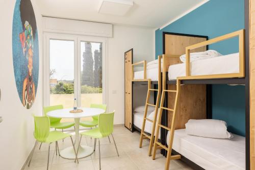 a room with a table and chairs and bunk beds at Ostello della Gioventù Brindisi in Brindisi