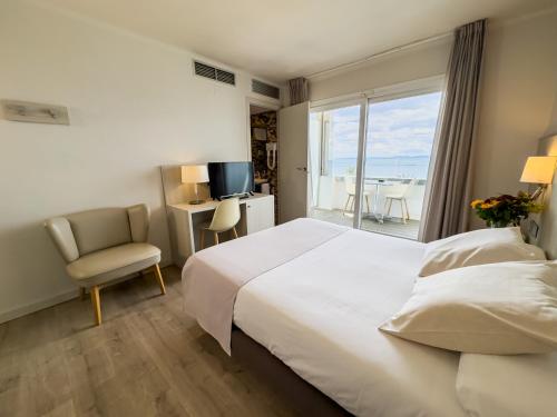 Hotel Marina في روساس: غرفه فندقيه بسرير وكرسي ونافذه