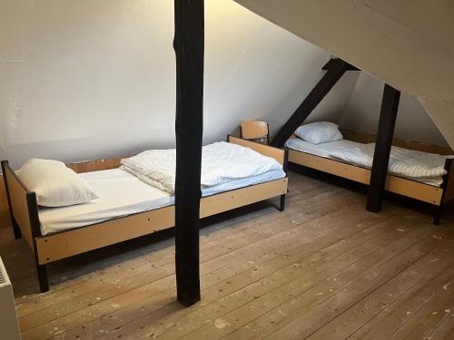 two beds in a attic room with wooden floors at Waldschlösschen Ricklingen in Hannover