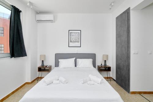 ein Schlafzimmer mit einem weißen Bett und zwei Nachttischen in der Unterkunft STUDIO Apartment Lugano SeaUAthens in Athen