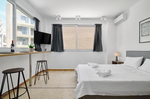 ein Schlafzimmer mit einem Bett und zwei Hockern sowie eine Küche in der Unterkunft STUDIO Apartment Lugano SeaUAthens in Athen