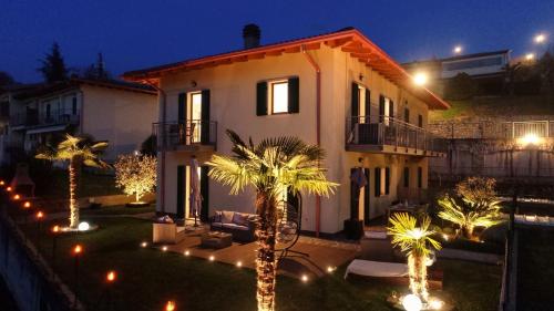 une maison avec des palmiers dans la cour la nuit dans l'établissement SalvatoreHomes - Luxury Villa with private Garden & BBQ, à San Zeno di Montagna