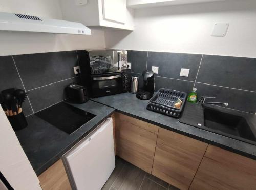 a small kitchen with a sink and a microwave at Studio proche centre-ville in Dax