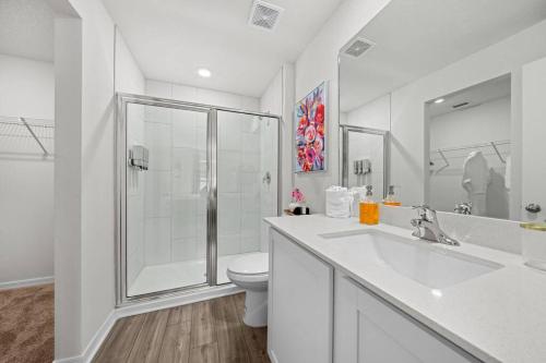 a white bathroom with a shower and a toilet at Brand New Theme House w Game Room - Encanta Magical in Palm Bay