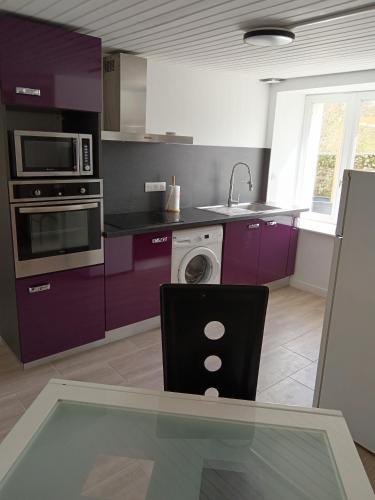 une cuisine avec des placards violets et une table en verre dans l'établissement Gîte Le well wazh, à Plouray