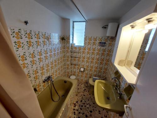 een badkamer met een geel bad en een wastafel bij Lourantos Studios & Apartments in Vathi