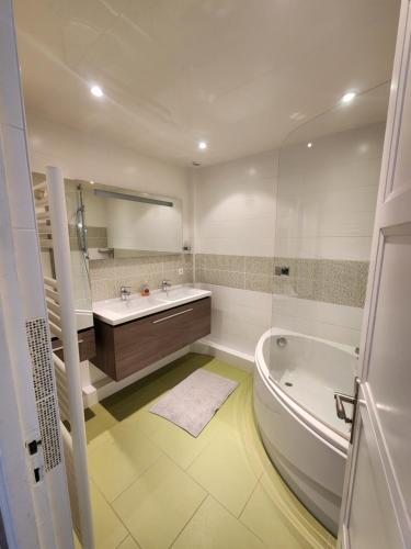 une salle de bain blanche avec une baignoire et un lavabo dans l'établissement Perle rare - Triangle d'or -98m2 - 6 pers, à Caen