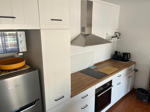 une petite cuisine avec des armoires blanches et une cuisinière dans l'établissement Résidence l’Amiraute, à Bormes-les-Mimosas