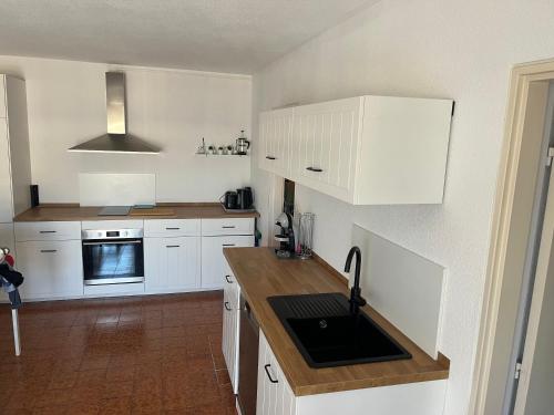 une cuisine avec des armoires blanches et un évier dans l'établissement Résidence l’Amiraute, à Bormes-les-Mimosas