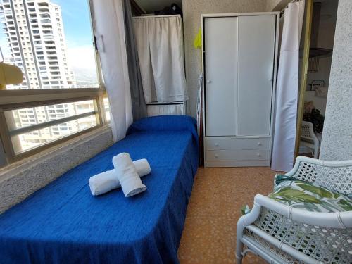 1 dormitorio con 1 cama azul y 2 toallas en Apartamento Mariscal 4, 13 con piscina y vistas al mar, en Benidorm