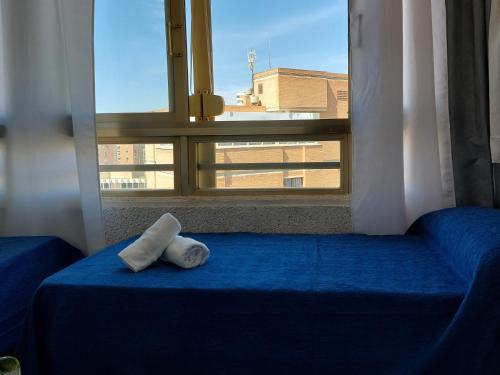 una almohada sentada en una cama frente a una ventana en Apartamento Mariscal 4, 13 con piscina y vistas al mar, en Benidorm
