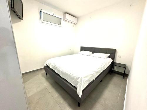 a bedroom with a bed with white sheets and a window at מיני דירת פנטהאוז in Rishon LeẔiyyon