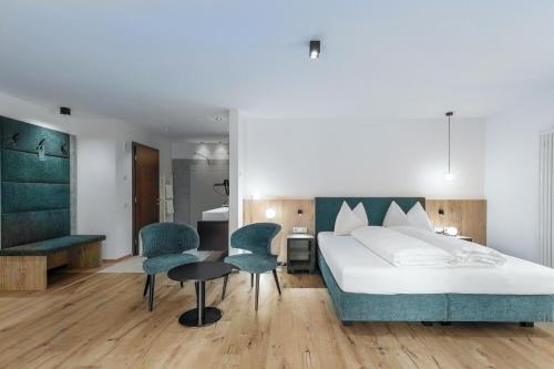 a bedroom with a bed and two chairs and a table at Hotel Alpenrose in San Valentino alla Muta