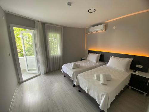 a hotel room with two beds and a window at Ayvalık Denizyıldızı Otel in Ayvalık
