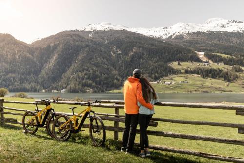 a woman standing next to a fence with two bikes at Hotel Alpenrose in San Valentino alla Muta