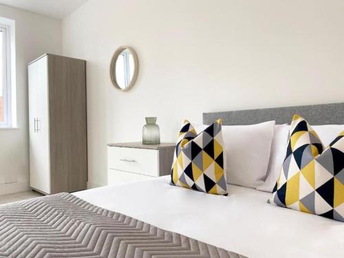 - une chambre dotée d'un grand lit blanc avec des oreillers jaunes et noirs dans l'établissement Cloud at Fleet Heights Apartment Two, à Fleet