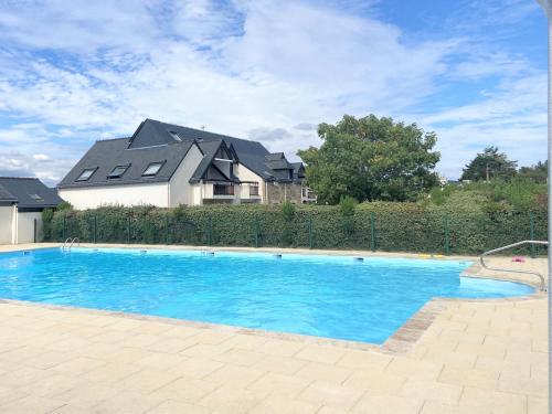 une grande piscine bleue devant une maison dans l'établissement REFLETS - Duplex avec balcon, Piscine - T110, à Carnac