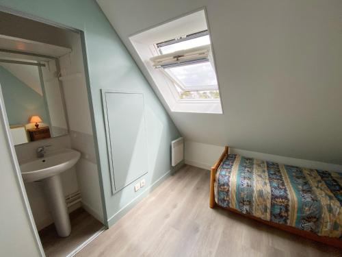 une salle de bain avec un lit, un lavabo et une lucarne dans l'établissement REFLETS - Duplex avec balcon, Piscine - T110, à Carnac
