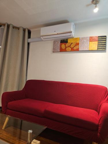 a red couch sitting in a living room with a air conditioner at San Ignacio Suite Apartments in Santiago