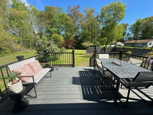 a wooden deck with a bench and a table at Charming Connecticut Hideaway in Middlefield