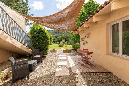 a patio with chairs and a table next to a house at Maison Marvic, Le Laurier T2 in Apt