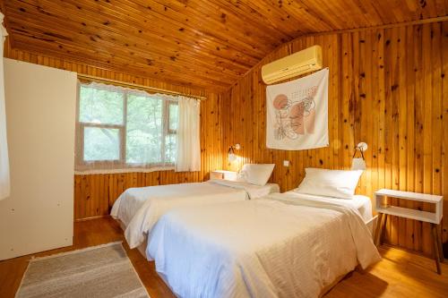 two beds in a room with wooden walls at Kibala Hotel in Cıralı
