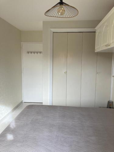 une pièce vide avec des armoires blanches et un luminaire dans l'établissement Bord de mer, à Saint-Raphaël