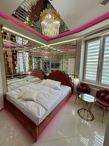 a bedroom with a large bed and a chandelier at Apartament "Gold Luxury Dubai" Centrum z dużą wanną dla Dwojga in Gniezno