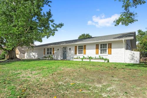 a white house with a tree in the yard at Ranch Home Gem 5BR Home Sleeps 12 with Game Room in Gulfport