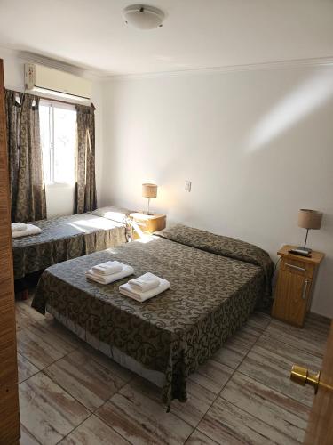 a hotel room with two beds and a window at Hotel Geminis in Mendoza