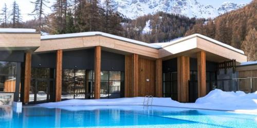 a building with a swimming pool in the snow at Vars, Appart spacieux rénové 4 couchages dans chalet in Vars