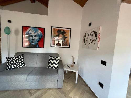 uma sala de estar com um sofá cinzento e quadros na parede em Luxuria em Iglesias