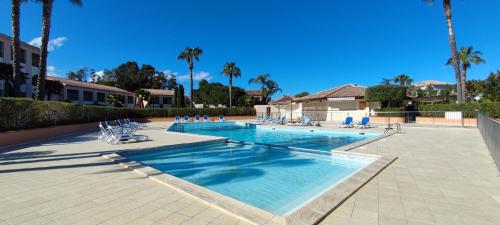 une grande piscine avec chaises et palmiers dans l'établissement Appartement T3 Marine de Bravone proche mer, à Linguizzetta