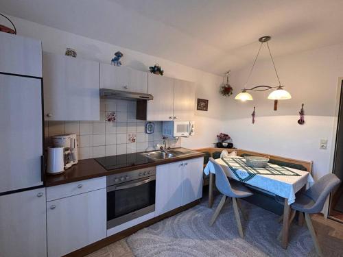 a kitchen with white cabinets and a table with a sink at Ferienwohnungen Thalmeier in Sankt Gilgen