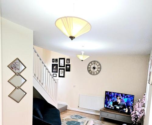 a living room with a tv and a clock on the wall at Beautiful Townhouse with Netflix in Long Eaton