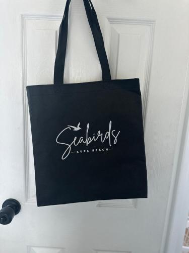 a black tote bag hanging on a door at Seabirds Motel At Kure Beach in Kure Beach