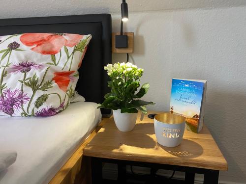 a table with a plant and a book on a bed at Haus Deutsche Bucht in Borkum