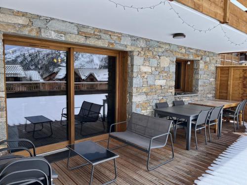 un patio avec des tables et des chaises et un mur en pierre dans l'établissement Appartement de standing 8 au pied des pistes - OLVERA 202, à Valmeinier