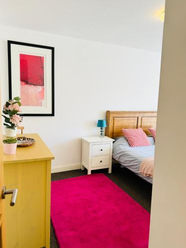 a bedroom with a bed and a pink rug at Modern house in central St Leonards in Hastings