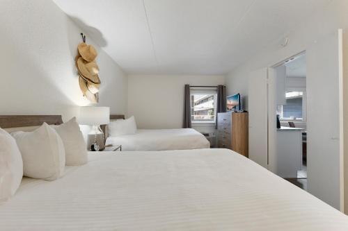 a white bedroom with two beds and a window at Beachcomber Resort in Avalon