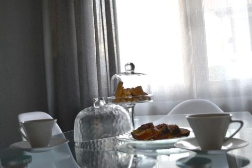 a glass table with a plate of food and two cups at Meteora Mosaico House in Kastrákion