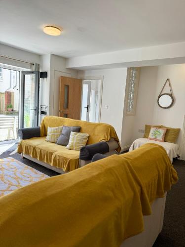 a living room with a couch with yellow sheets at Modern house in central St Leonards in Hastings