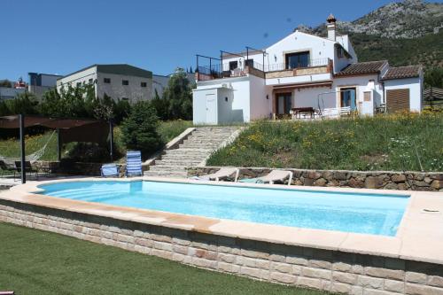 a swimming pool with a house in the background at Apartamento Valle del Guadiaro in Cortes de la Frontera