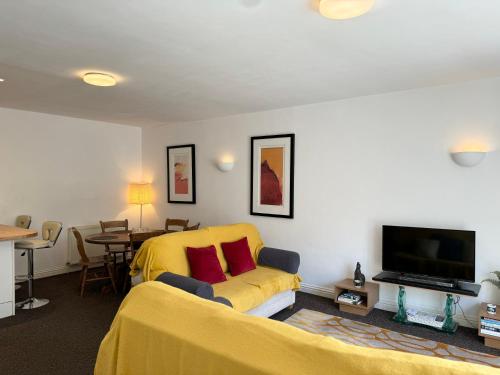 a living room with a yellow couch and a tv at Modern house in central St Leonards in Hastings