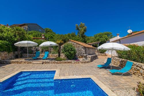 a pool with chairs and umbrellas next to a house at Villa Neva - Cizici, Krk in Čižići